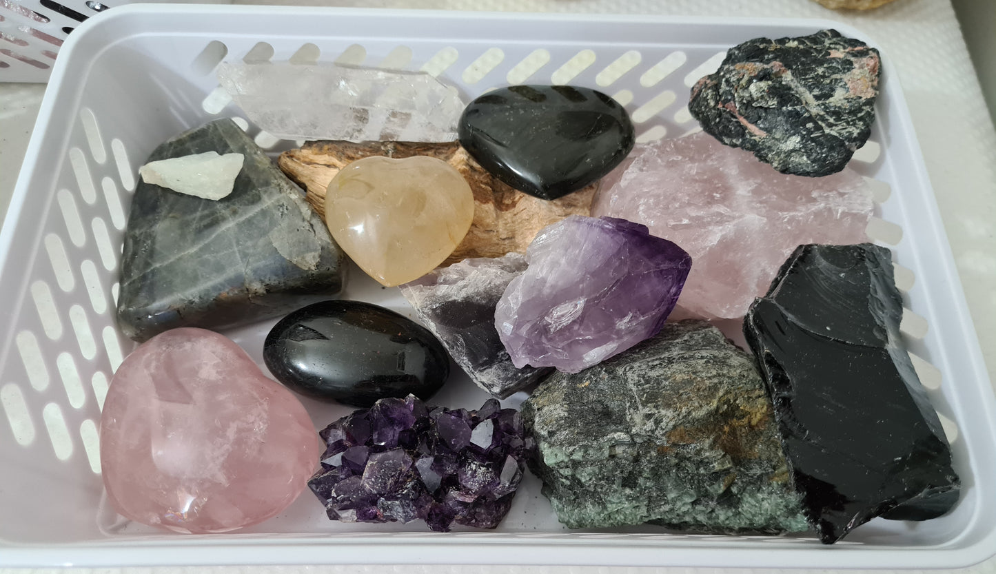 An assortment of mixed natural and polished crystals layed out in a basket