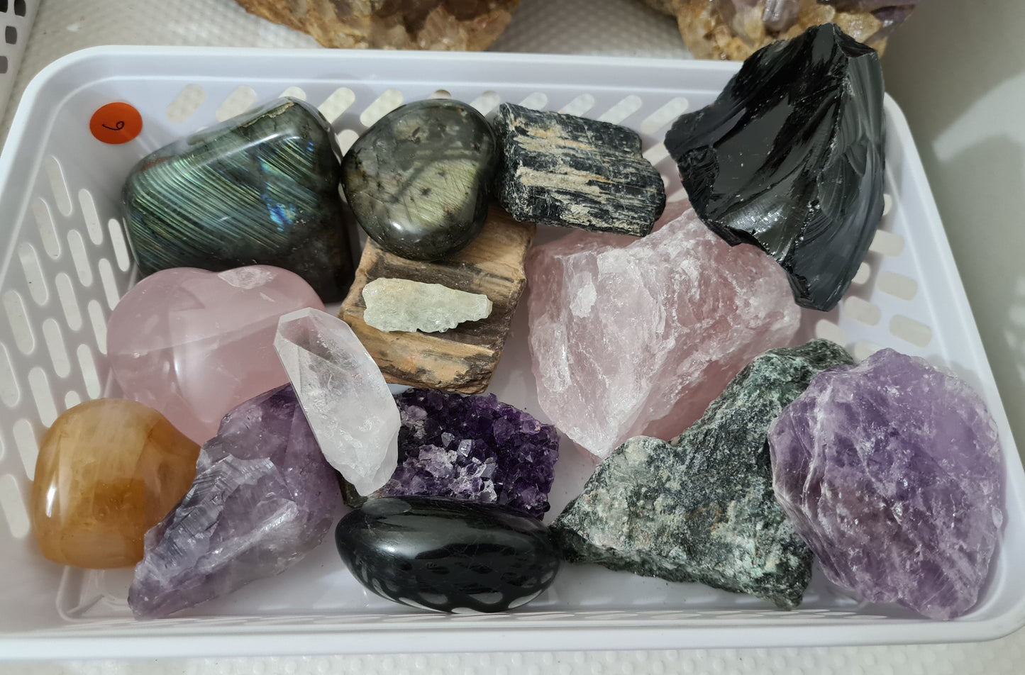An assortment of mixed natural and polished crystals layed out on a table