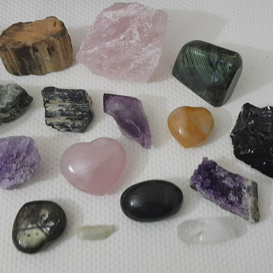 An assortment of mixed natural and polished crystals layed out on a table