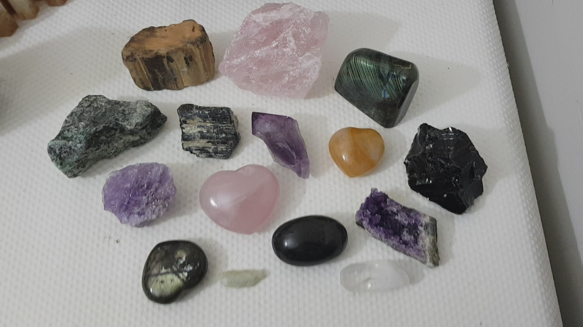 An assortment of mixed natural and polished crystals layed out on a table