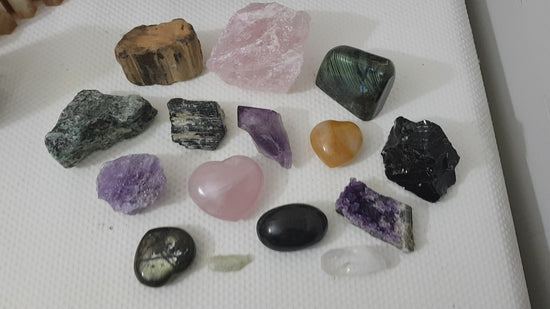 An assortment of mixed natural and polished crystals layed out on a table