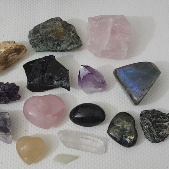 An assortment of mixed natural and polished crystals layed out on a table