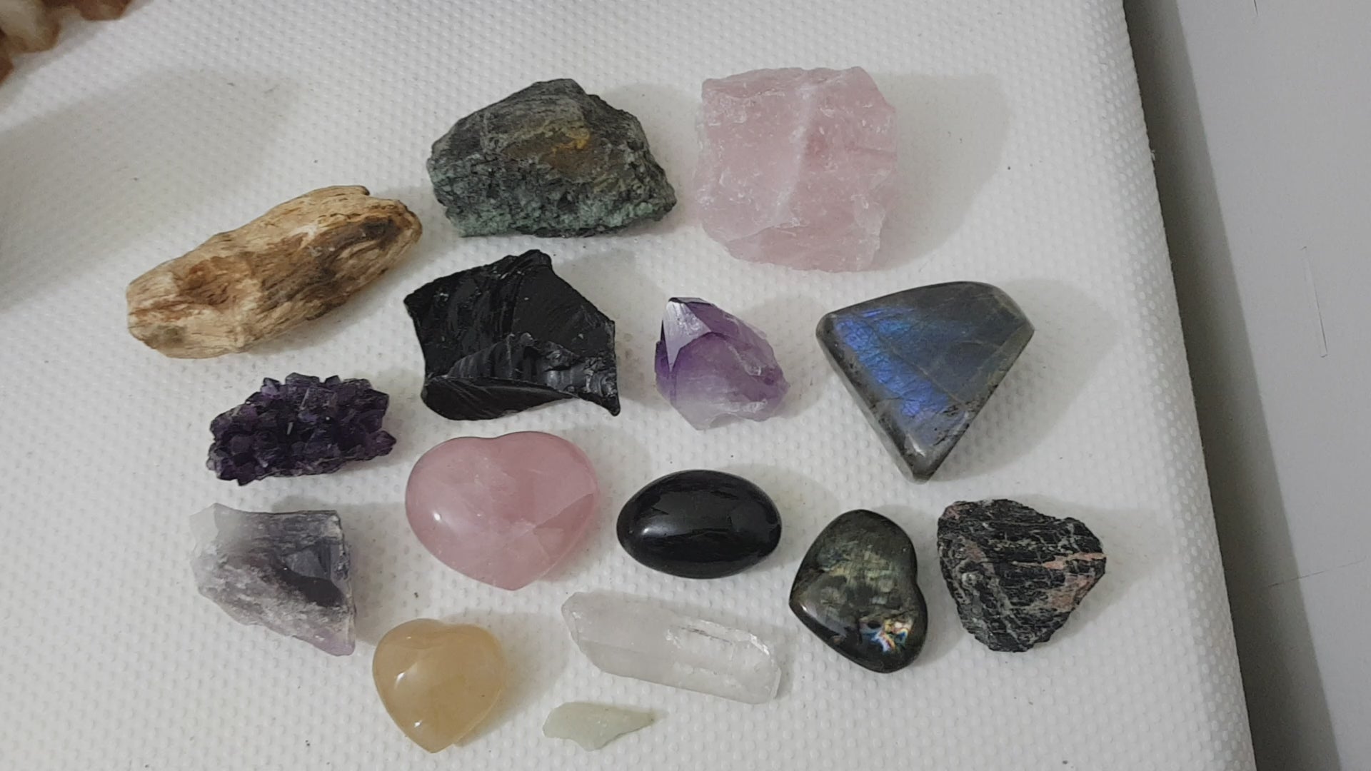An assortment of mixed natural and polished crystals layed out on a table