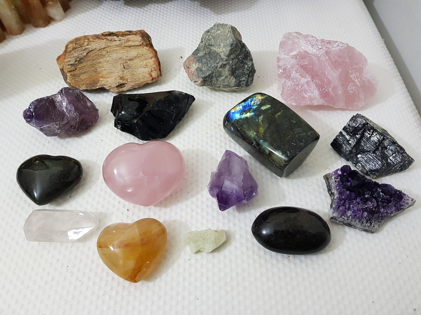 An assortment of mixed natural and polished crystals layed out on a table
