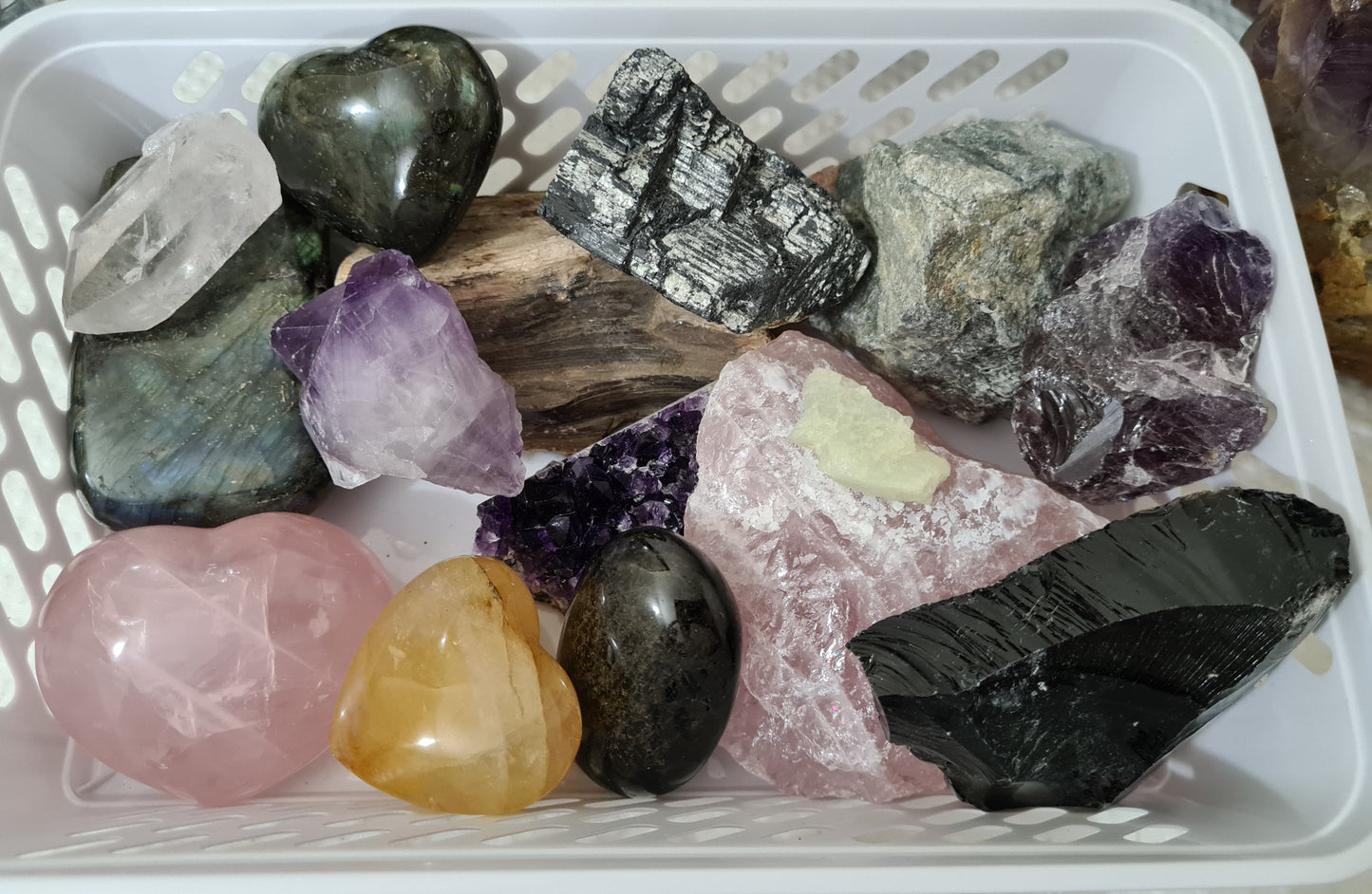 An assortment of mixed natural and polished crystals layed out in a basket