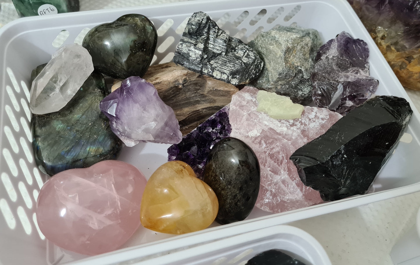 An assortment of mixed natural and polished crystals layed out in a basket