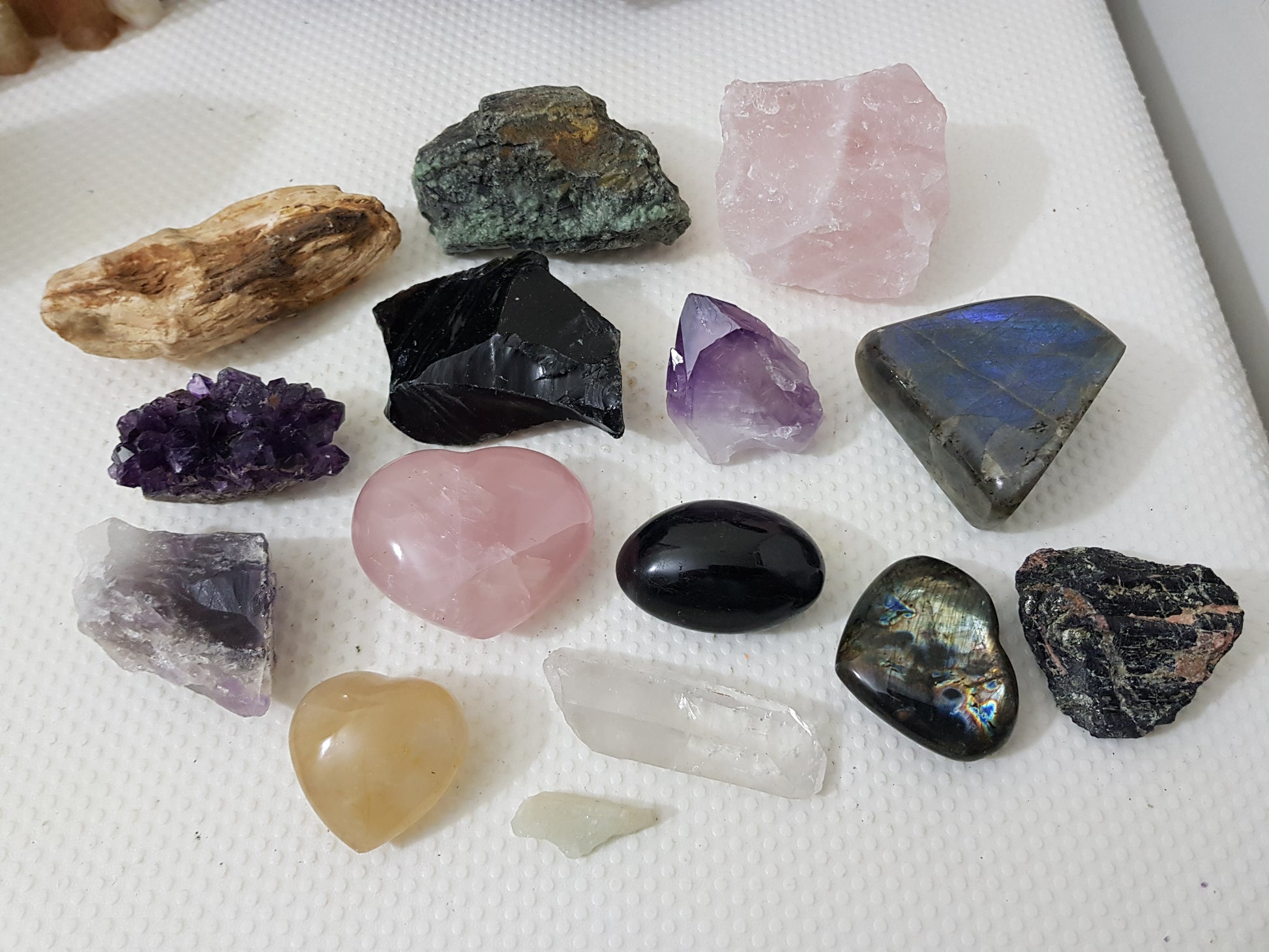 An assortment of mixed natural and polished crystals layed out on a table