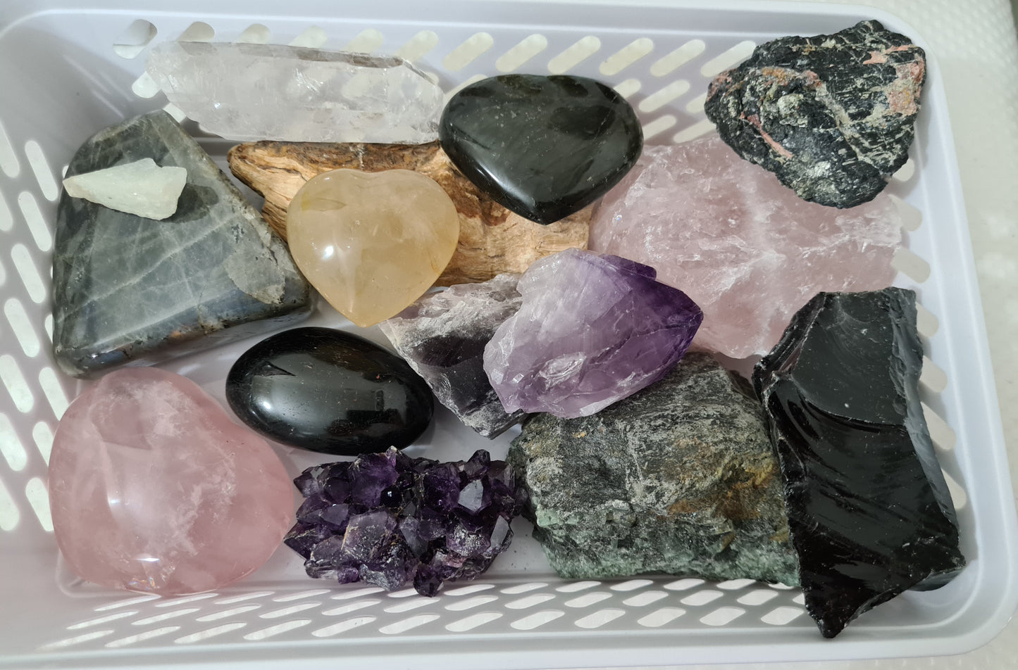An assortment of mixed natural and polished crystals layed out in a basket