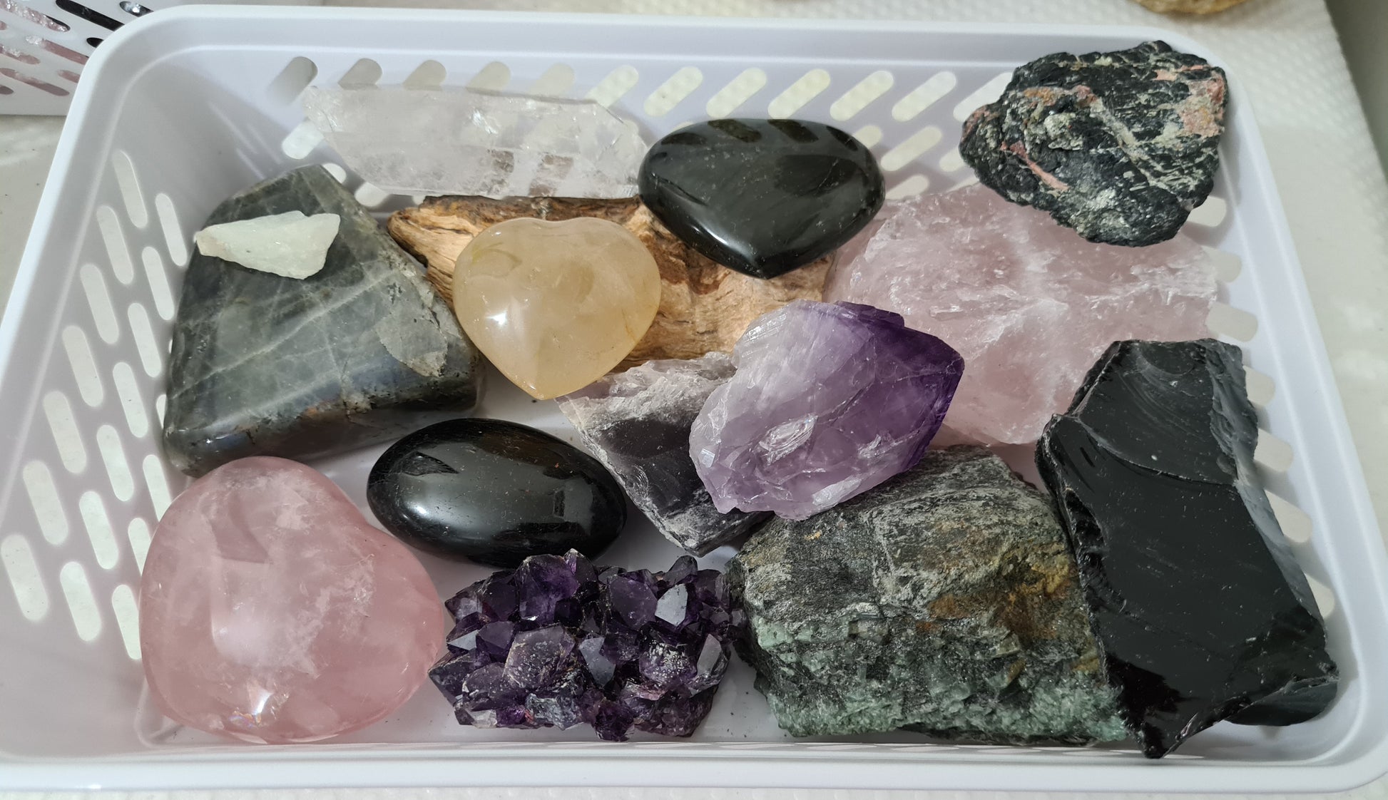 An assortment of mixed natural and polished crystals layed out in a basket