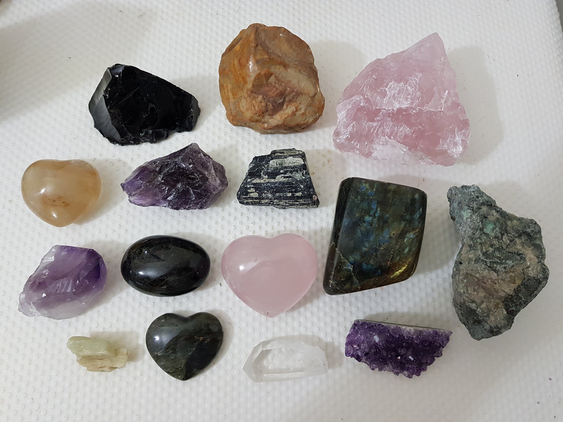 An assortment of mixed natural and polished crystals layed out on a table
