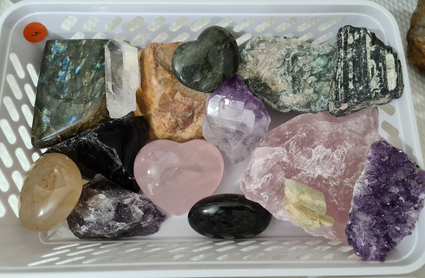 An assortment of mixed natural and polished crystals layed out in a small basket