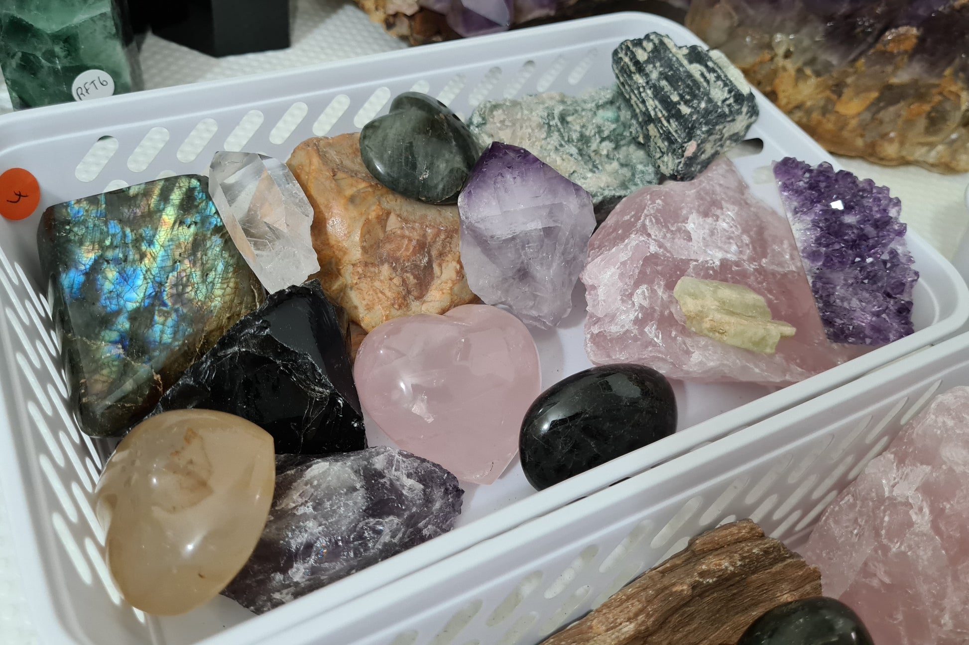 An assortment of mixed natural and polished crystals layed out in a small basket