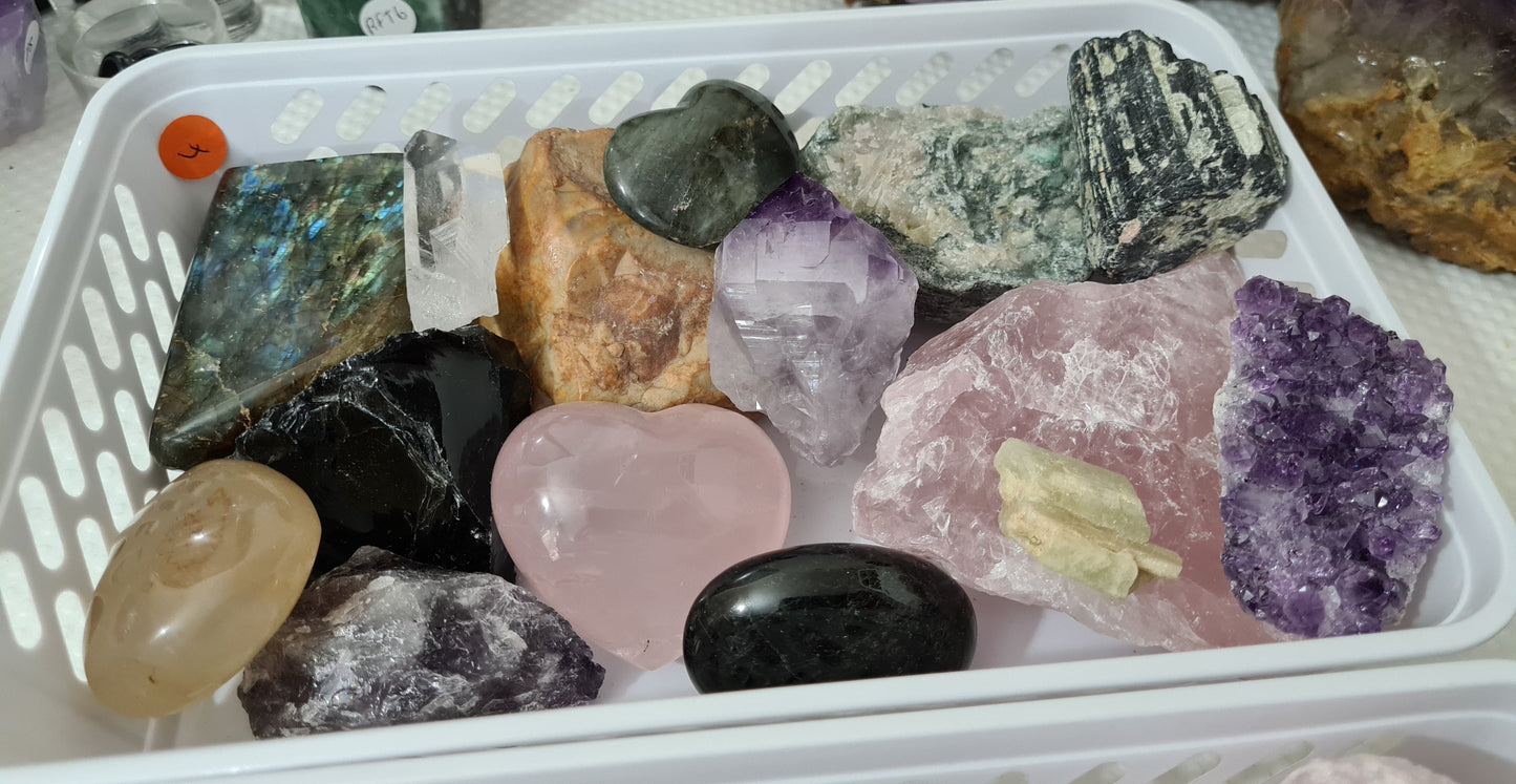 An assortment of mixed natural and polished crystals layed out in a small basket
