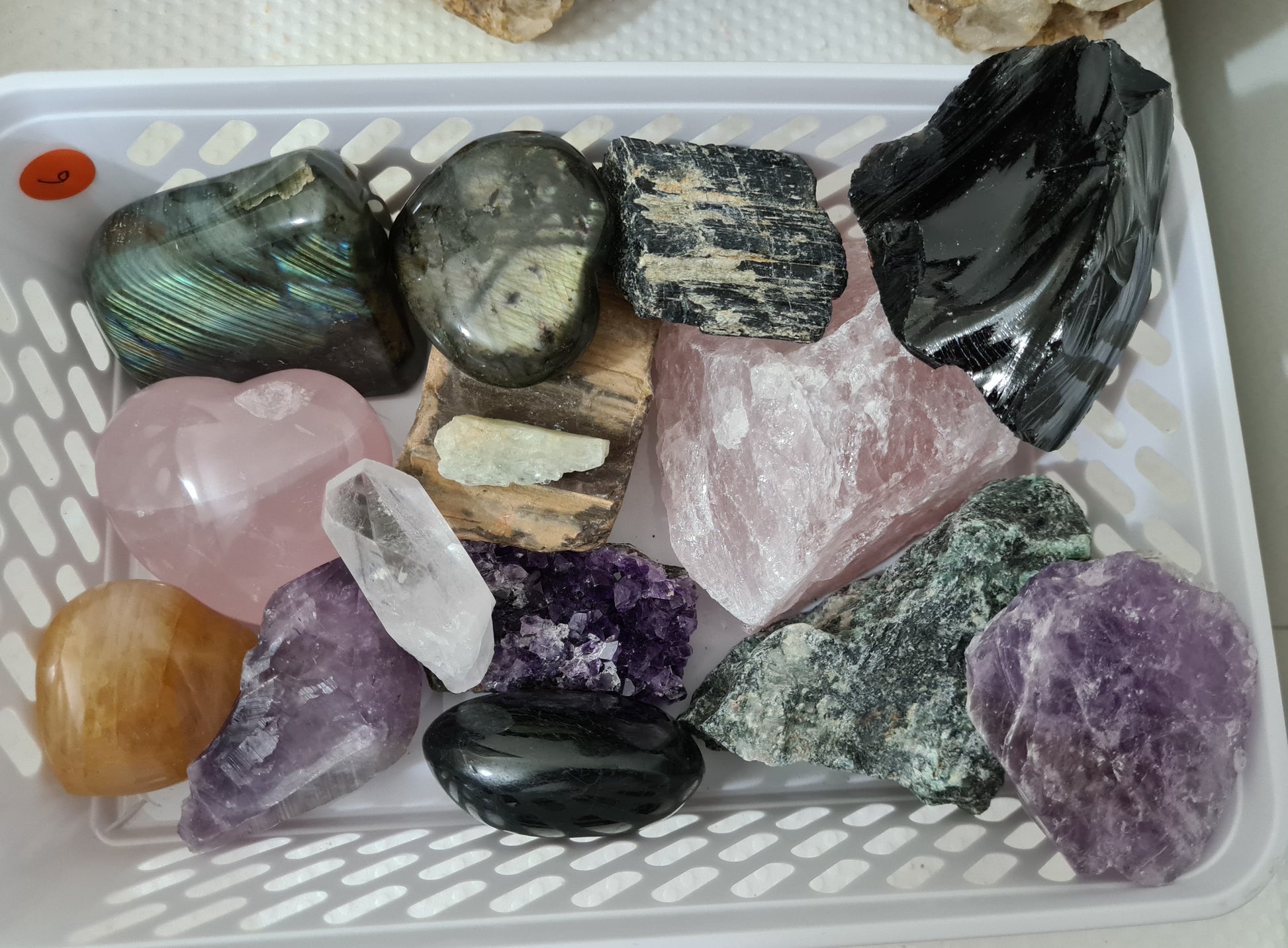 An assortment of mixed natural and polished crystals layed out on a table