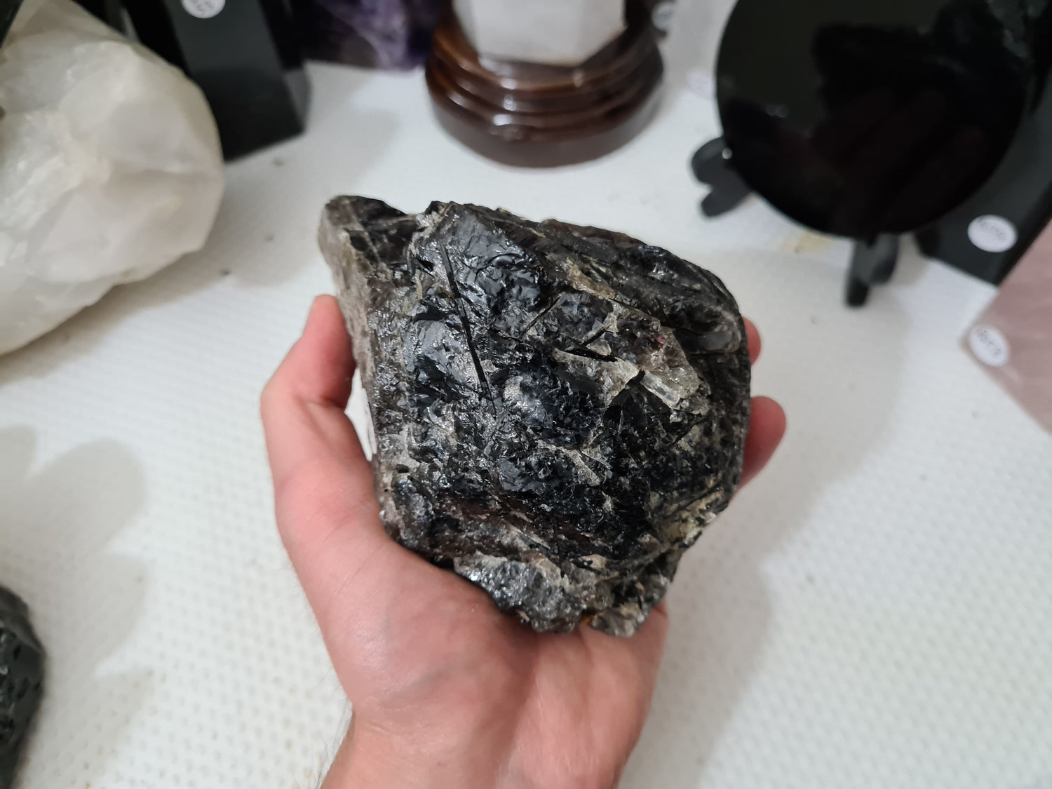 A hand holding a natural Smoky Quartz crystal chunk that is approximately 12.5 centimetres by 8.5 centimetres in size