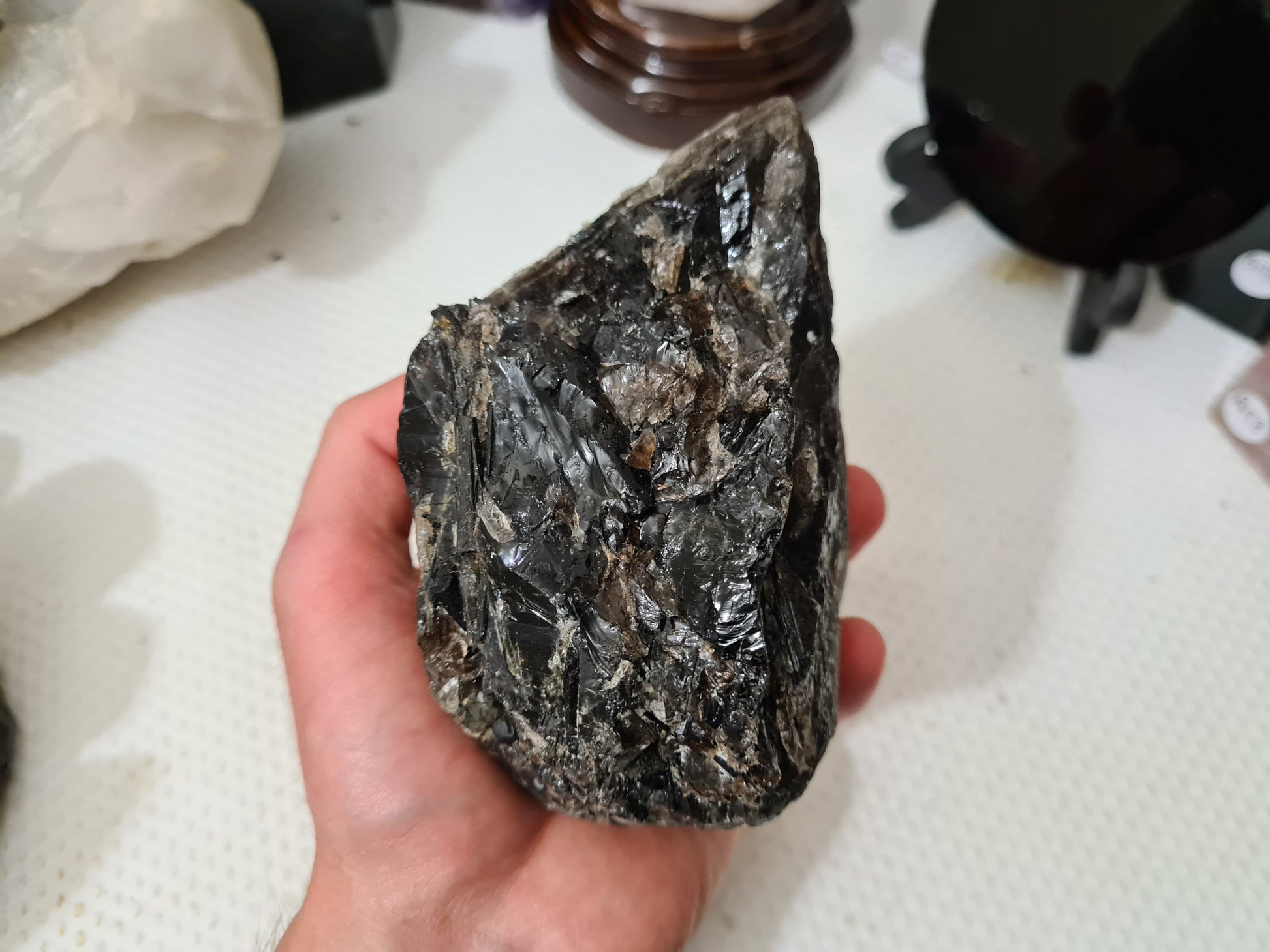 A hand holding a natural Smoky Quartz crystal chunk that is approximately 12.5 centimetres by 8.5 centimetres in size