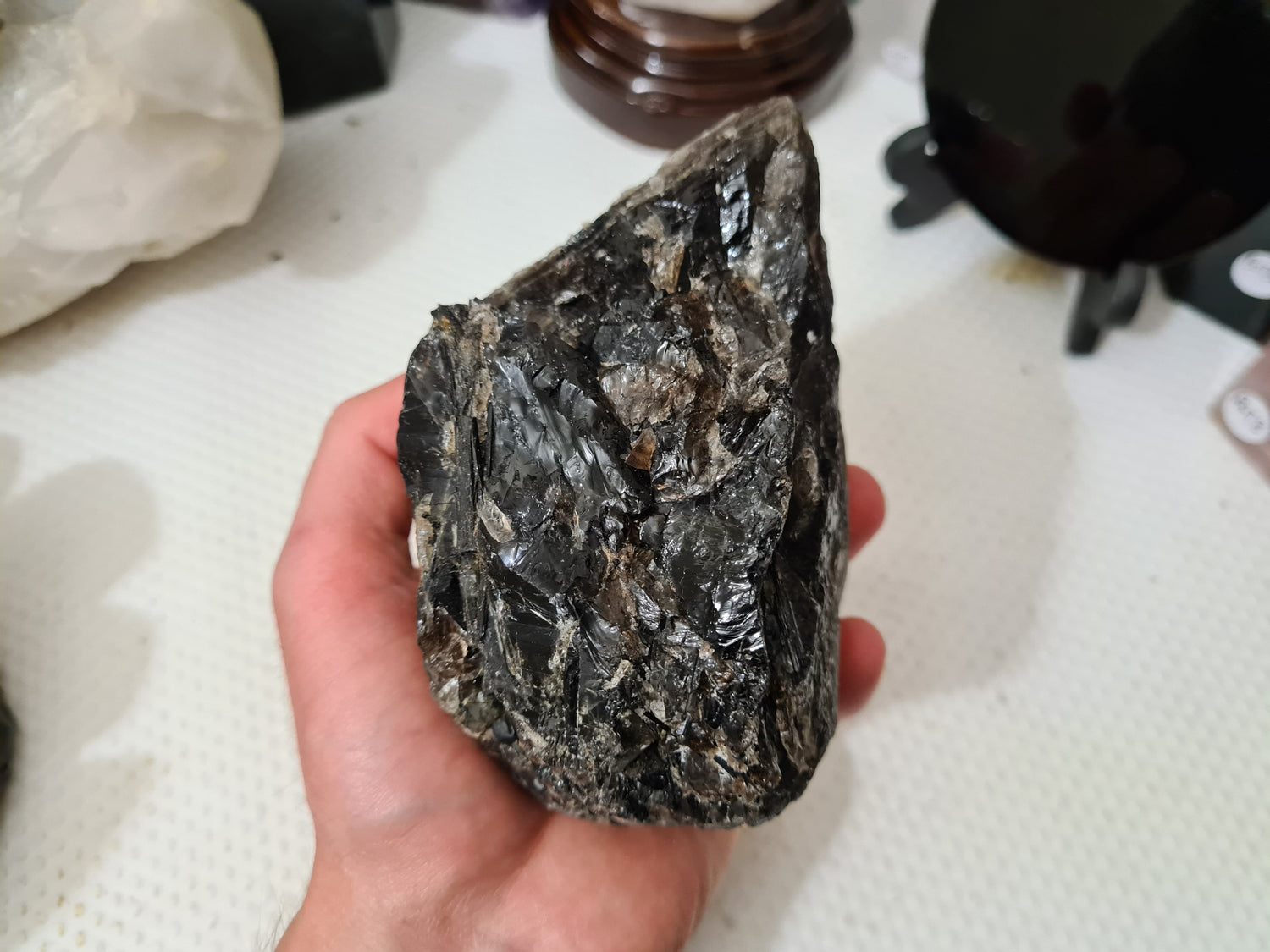 A hand holding a natural Smoky Quartz crystal chunk that is approximately 12.5 centimetres by 8.5 centimetres in size