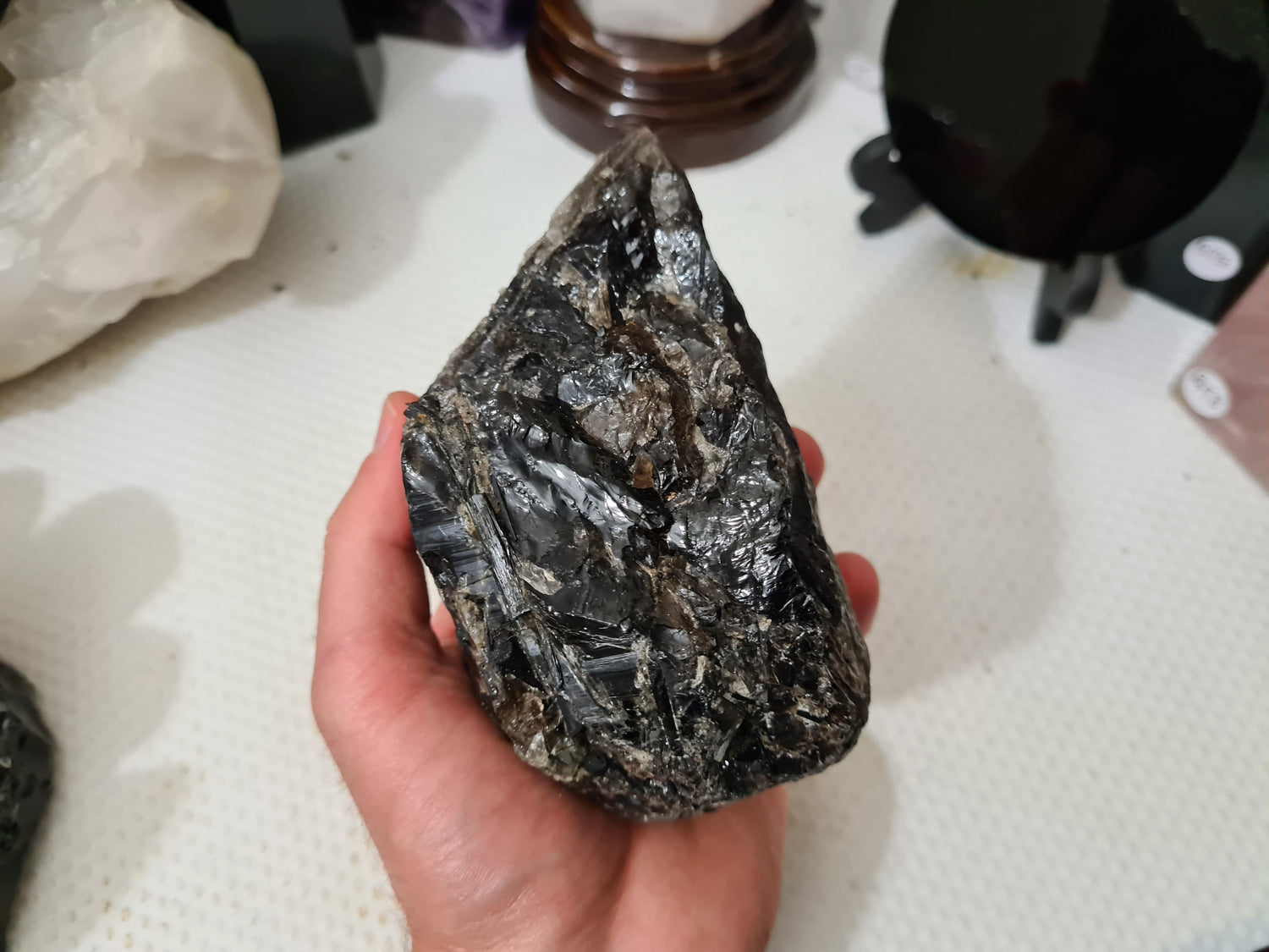 A hand holding a natural Smoky Quartz crystal chunk that is approximately 12.5 centimetres by 8.5 centimetres in size