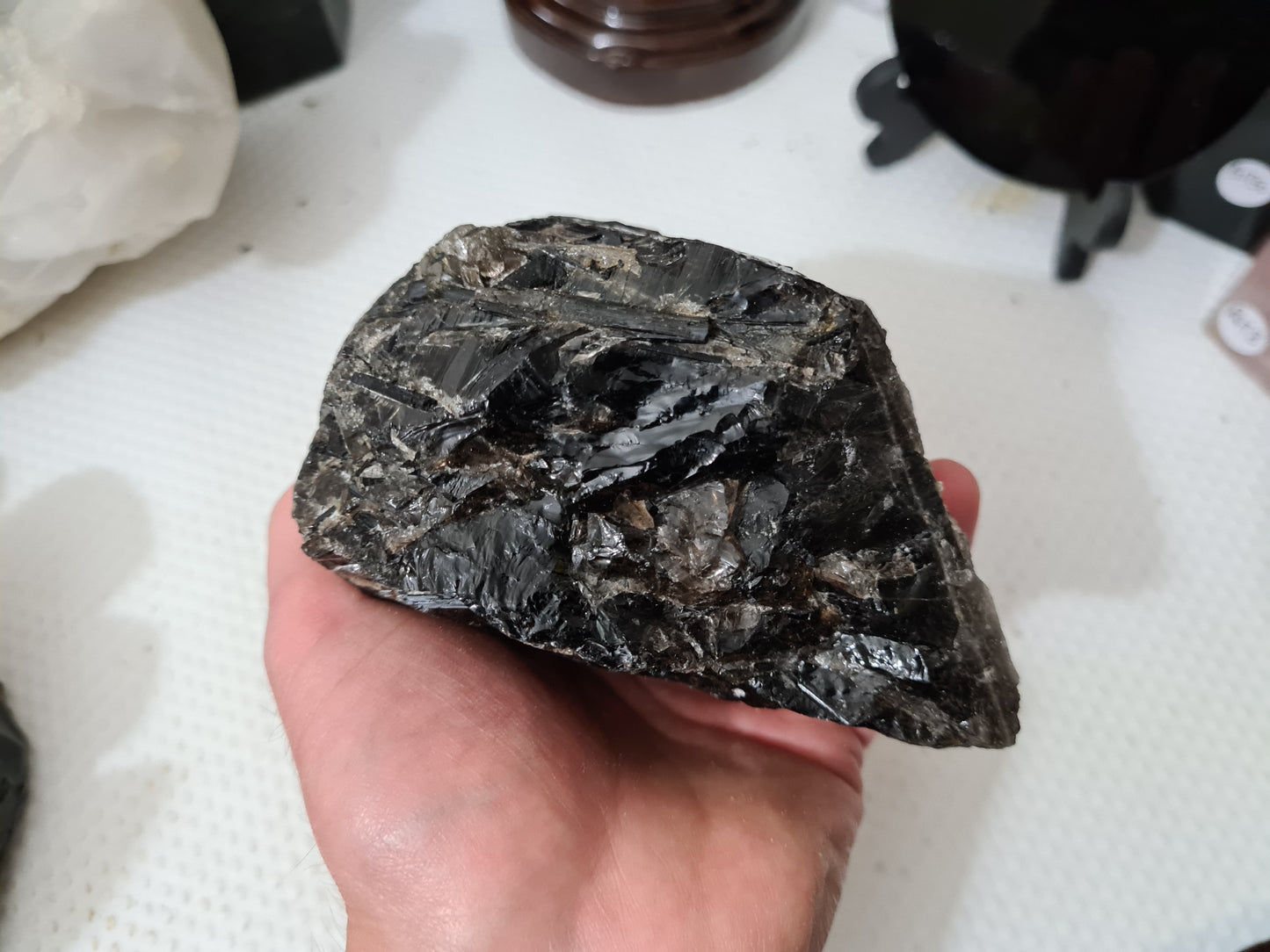A hand holding a natural Smoky Quartz crystal chunk that is approximately 12.5 centimetres by 8.5 centimetres in size