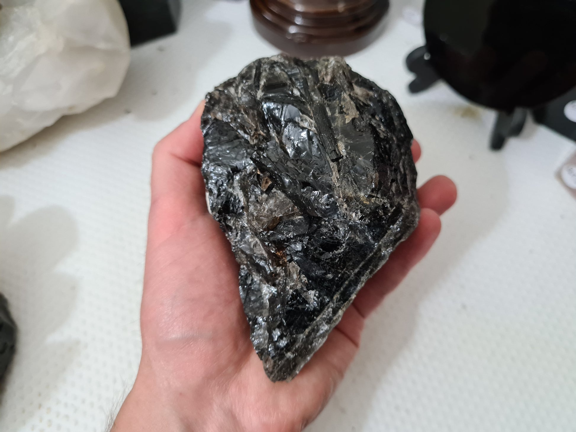 A hand holding a natural Smoky Quartz crystal chunk that is approximately 12.5 centimetres by 8.5 centimetres in size