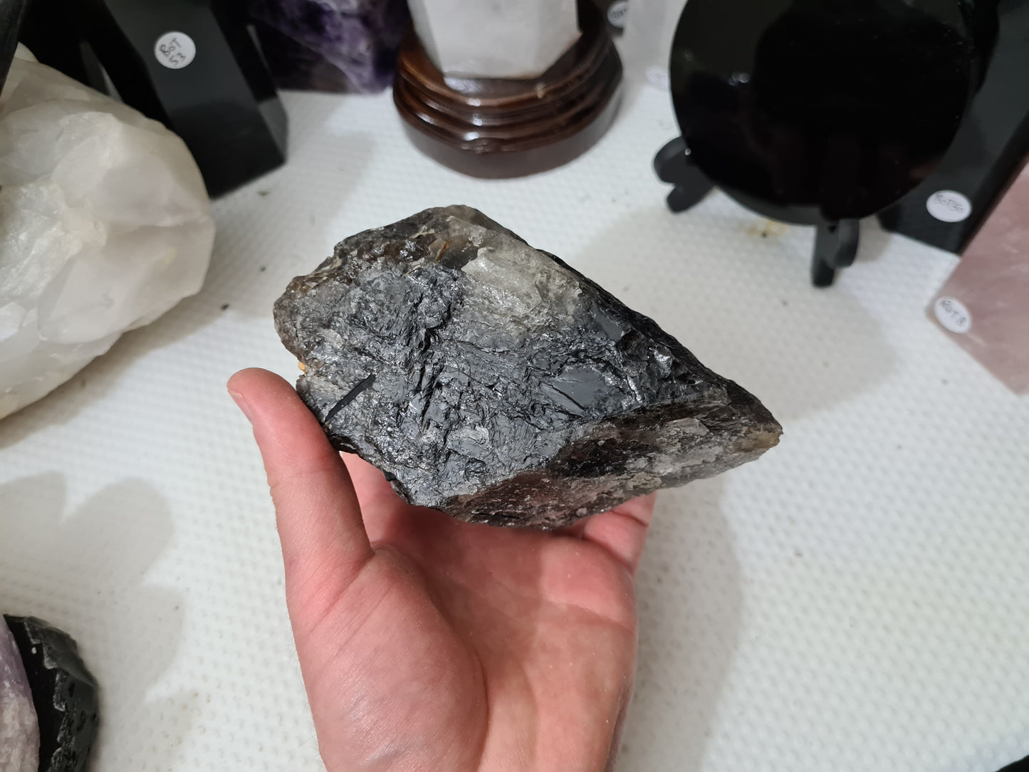 A hand holding a natural Smoky Quartz crystal chunk that is approximately 12.5 centimetres by 8.5 centimetres in size