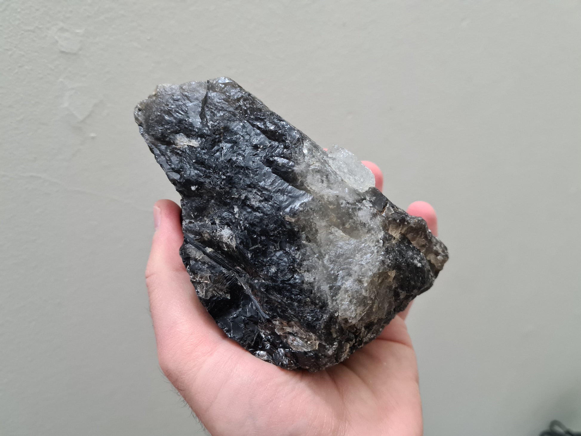 A hand holding a natural Smoky Quartz crystal chunk that is approximately 12.5 centimetres by 8.5 centimetres in size