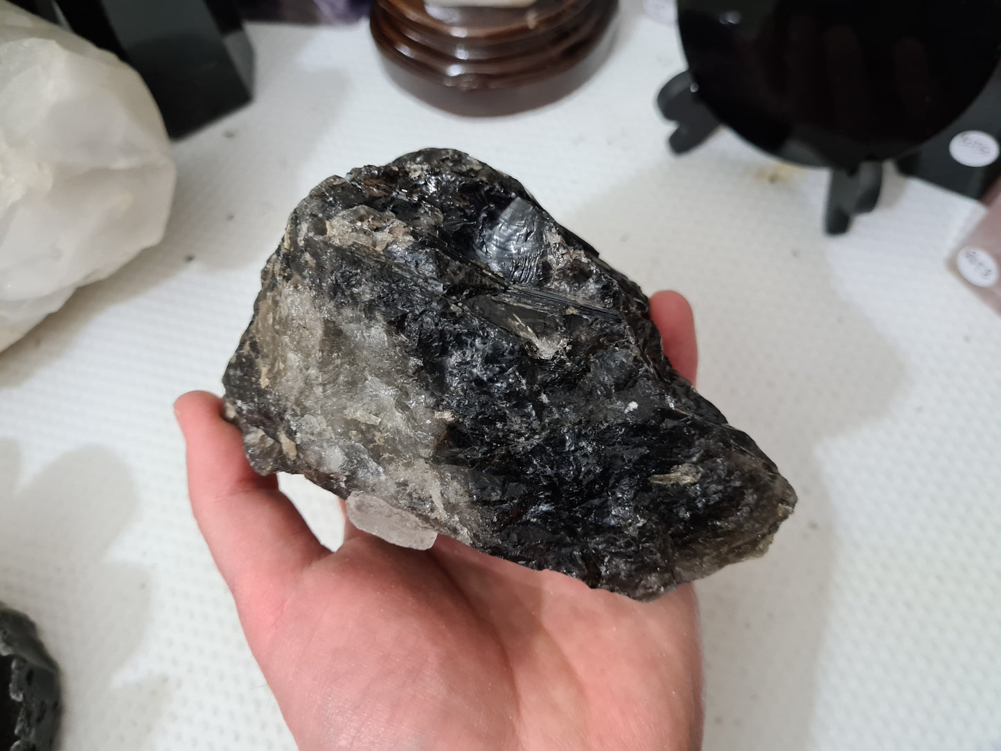 A hand holding a natural Smoky Quartz crystal chunk that is approximately 12.5 centimetres by 8.5 centimetres in size