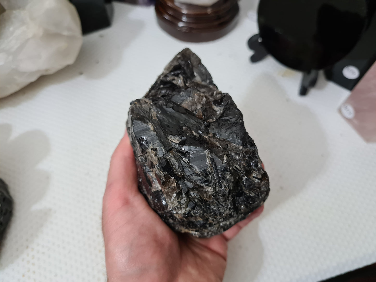 A hand holding a natural Smoky Quartz crystal chunk that is approximately 12.5 centimetres by 8.5 centimetres in size
