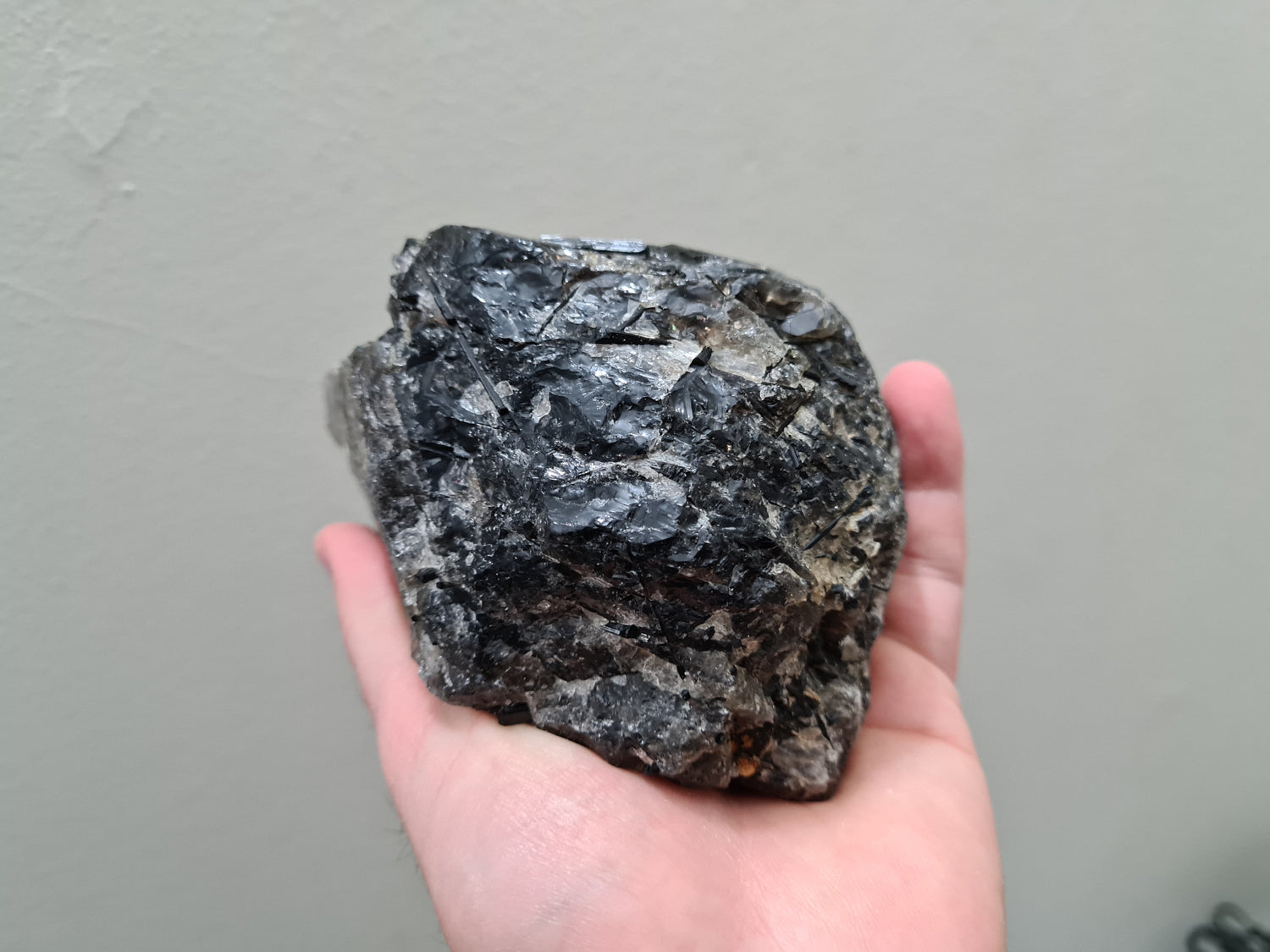 A hand holding a natural Smoky Quartz crystal chunk that is approximately 12.5 centimetres by 8.5 centimetres in size
