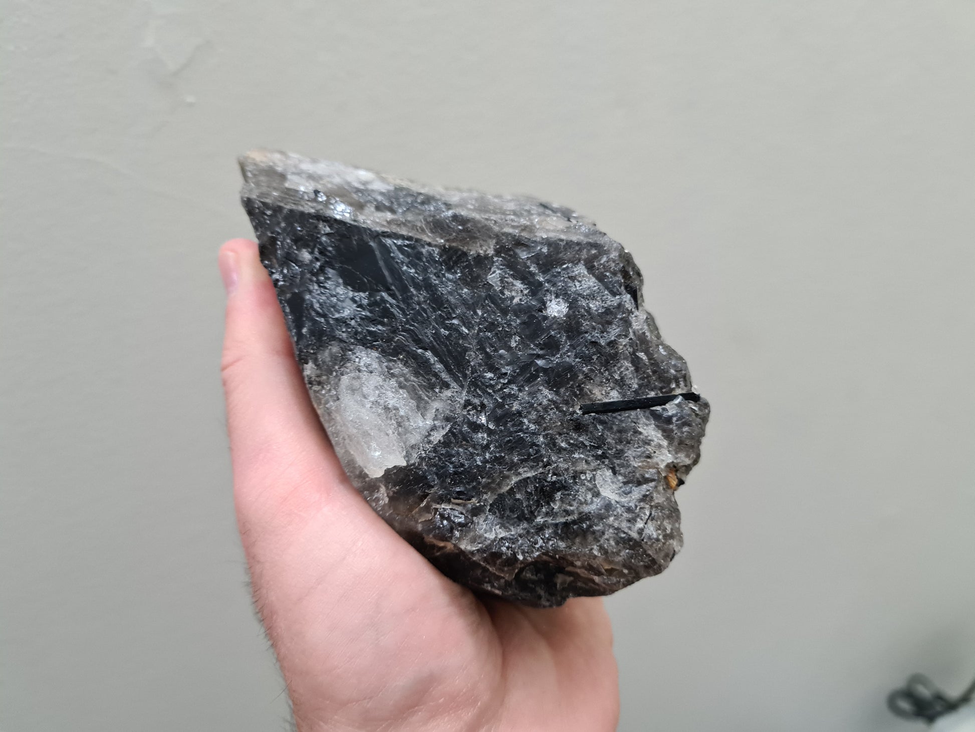 A hand holding a natural Smoky Quartz crystal chunk that is approximately 12.5 centimetres by 8.5 centimetres in size