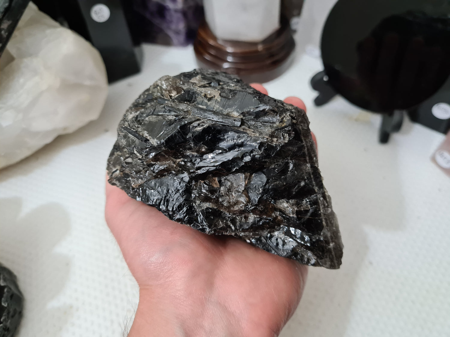 A hand holding a natural Smoky Quartz crystal chunk that is approximately 12.5 centimetres by 8.5 centimetres in size