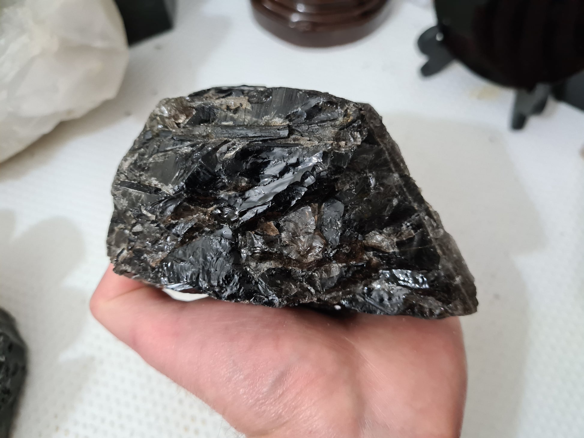 A hand holding a natural Smoky Quartz crystal chunk that is approximately 12.5 centimetres by 8.5 centimetres in size
