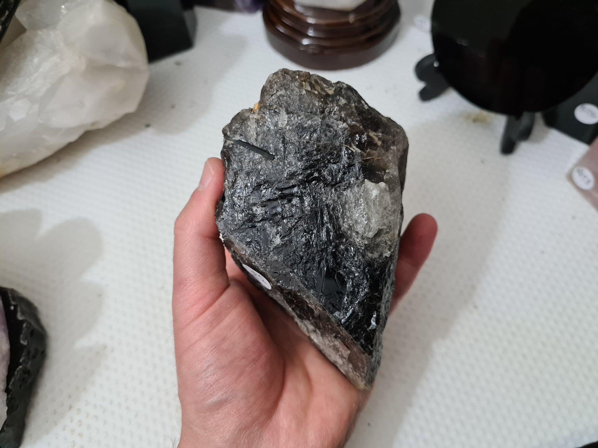 A hand holding a natural Smoky Quartz crystal chunk that is approximately 12.5 centimetres by 8.5 centimetres in size
