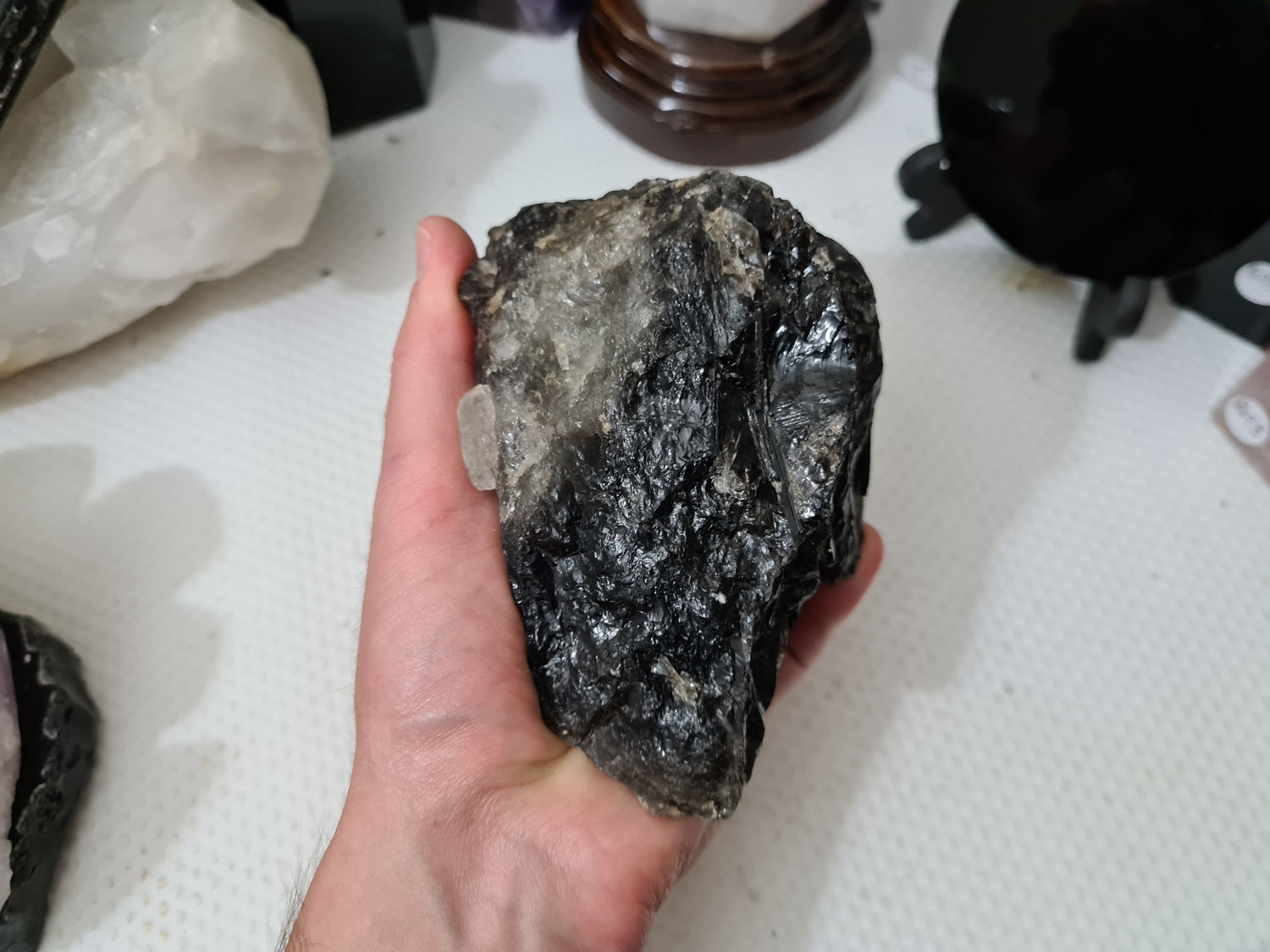 A hand holding a natural Smoky Quartz crystal chunk that is approximately 12.5 centimetres by 8.5 centimetres in size