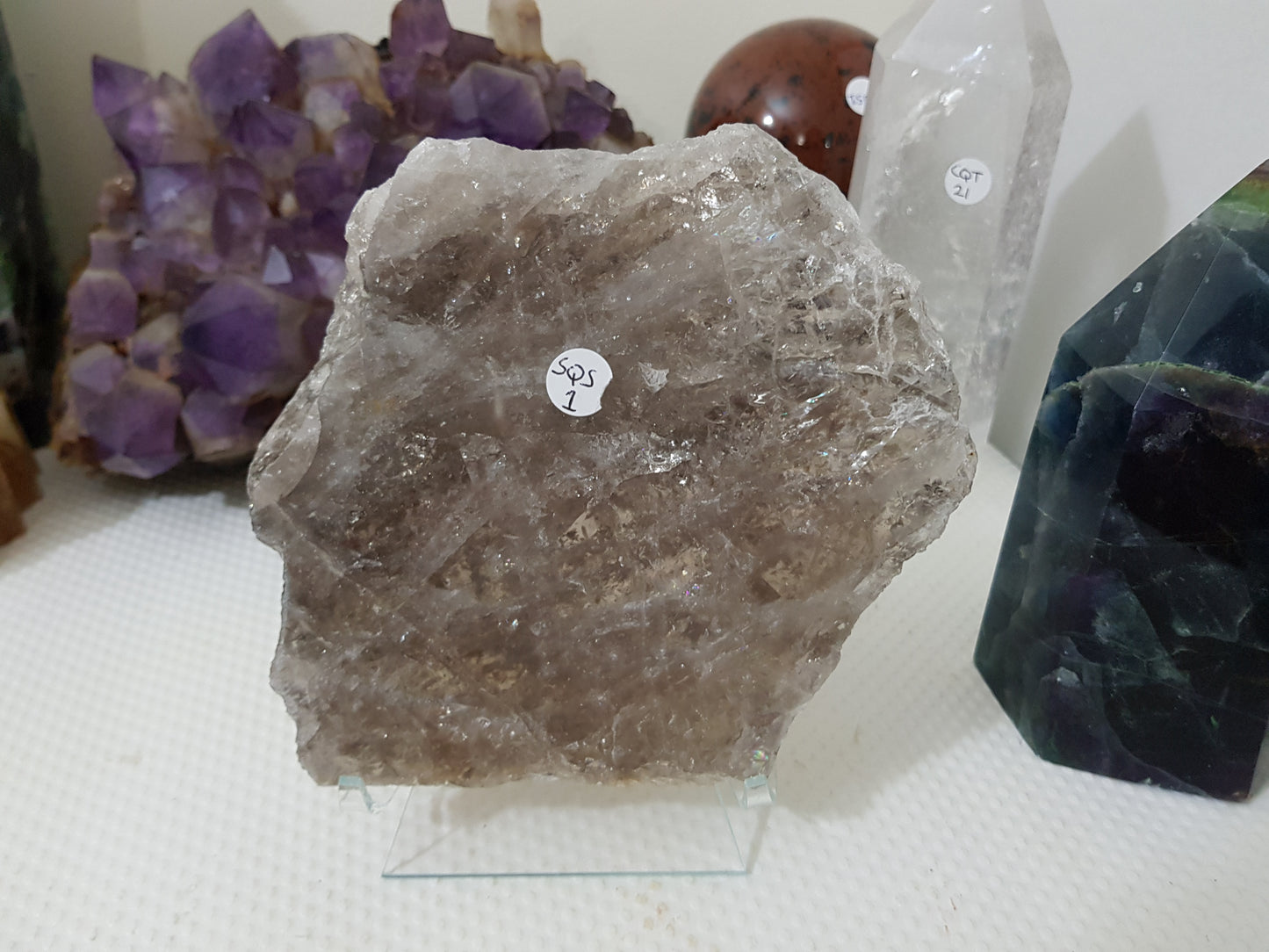 A large Smoky Quartz crystal slice that is approximately 15.5cm by 14cm in size resting on a display stand