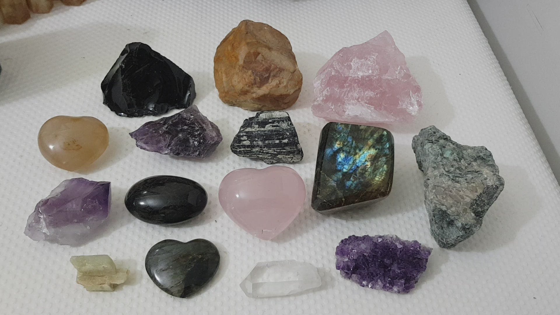 An assortment of mixed natural and polished crystals layed out on a table