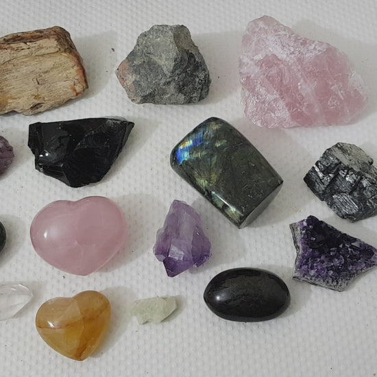 An assortment of mixed natural and polished crystals layed out on a table