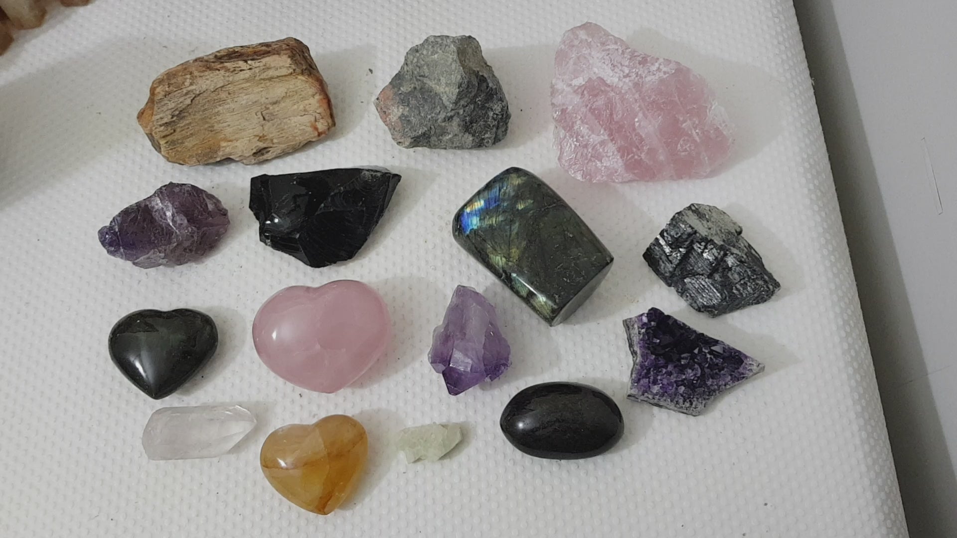 An assortment of mixed natural and polished crystals layed out on a table